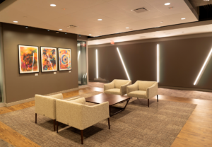 Linear lighting recessed in the walls and recessed downlights illuminate the seating area.