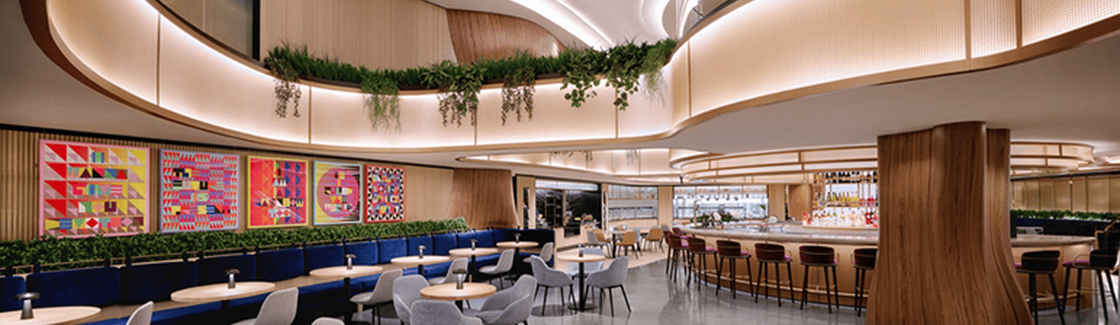 Restaurant and lounge with engaging ceiling design, swooping above with lighting and plants.