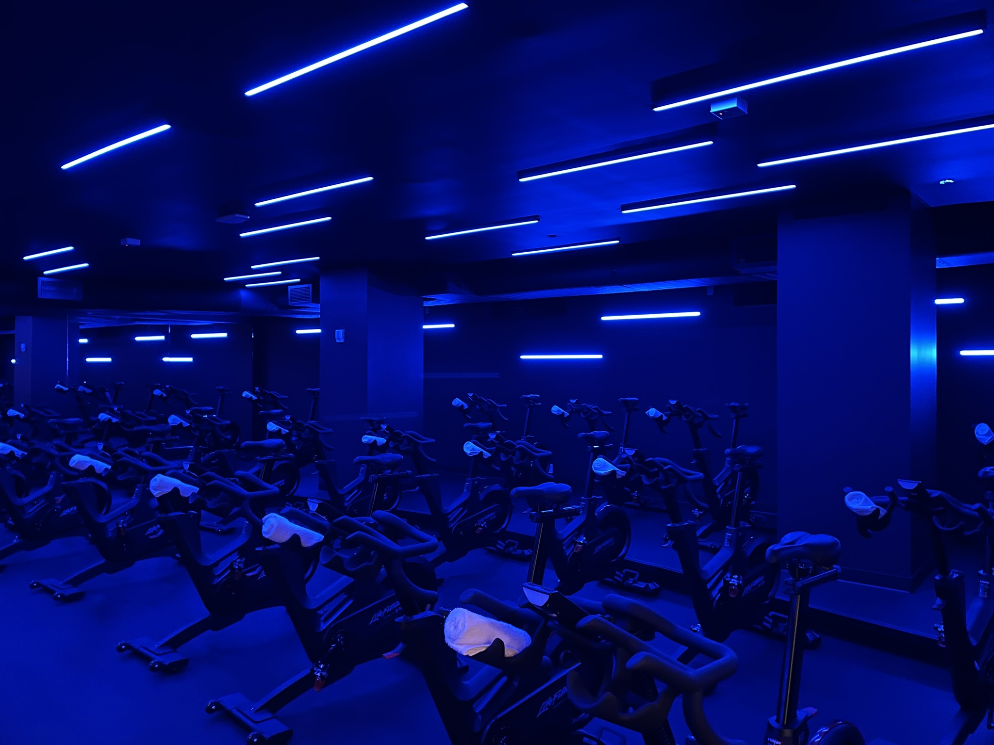 Workout studio with exercise bikes in a dramatically lit room.