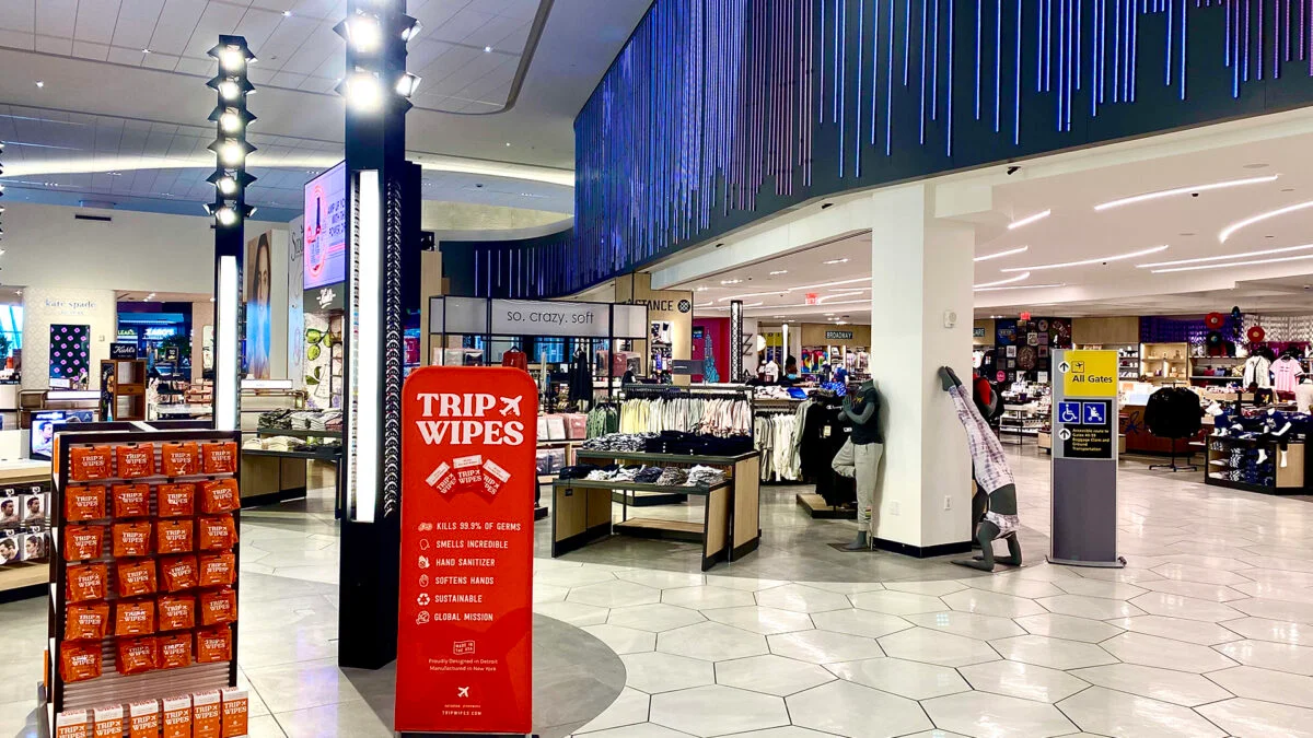Airport retail concourse with custom light poles, integrated linear ceiling lighting, and blue decorative lighting.