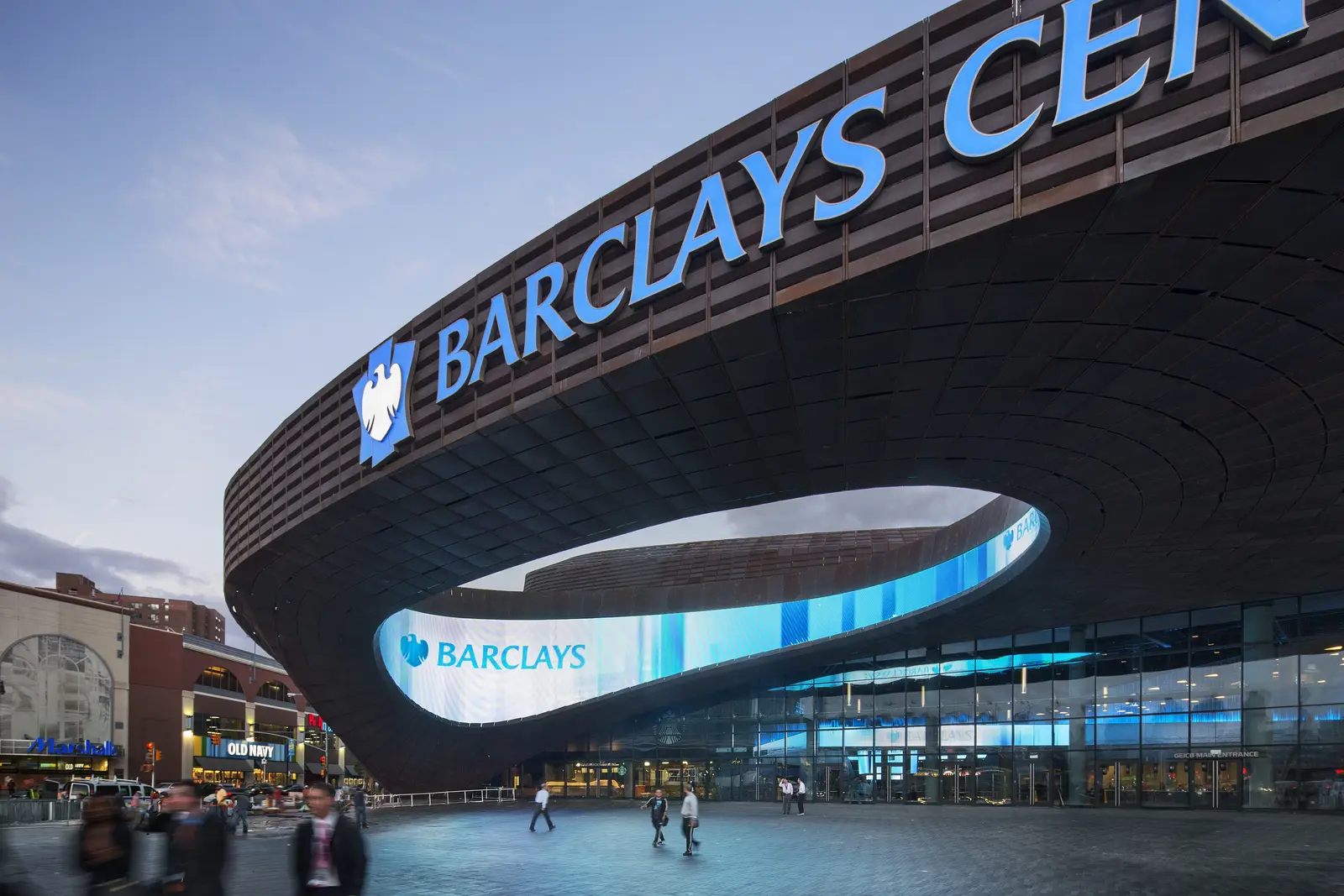 Exterior view of Barclays Center and its Corten steel oculus facade at dusk.