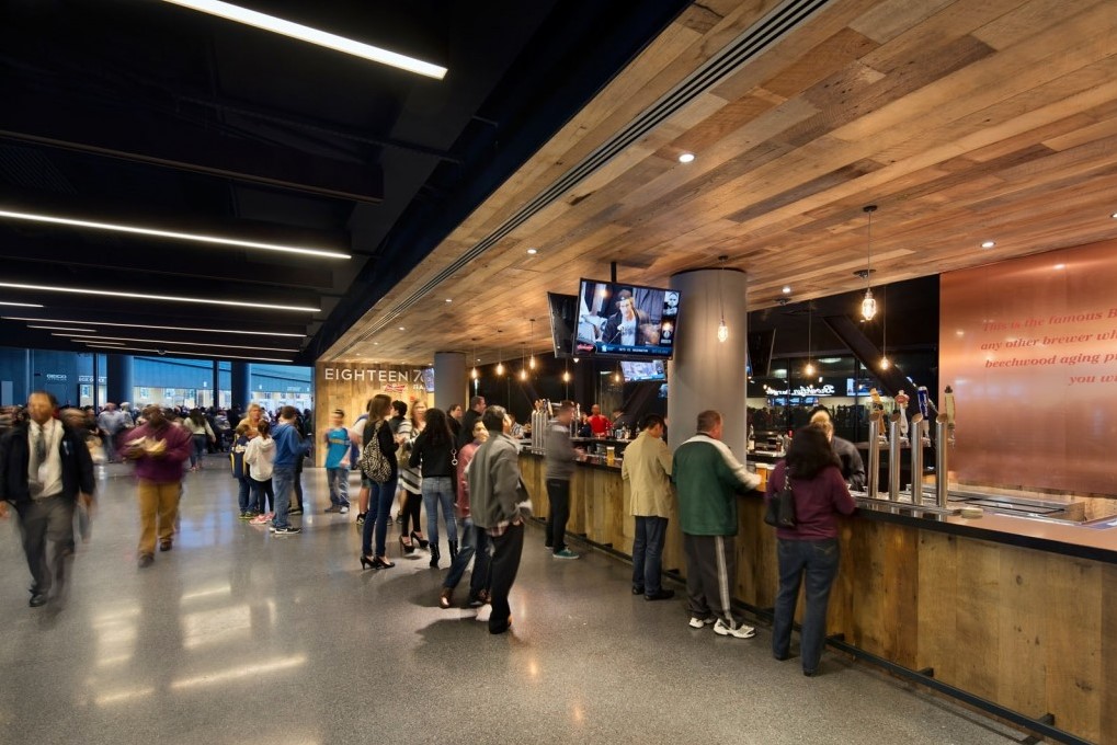 Barclays Center concourse with linear ceiling lighting and integrated lighting at the Eighteen76 bar.