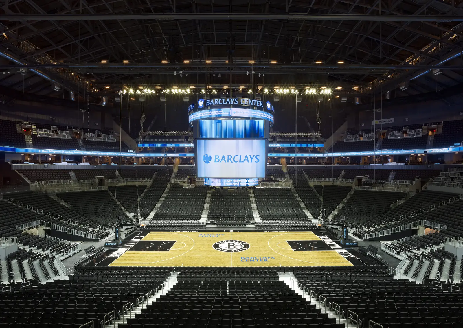 Barclays Center arena bowl with sports lighting illuminating the Brooklyn Nets basketball court.