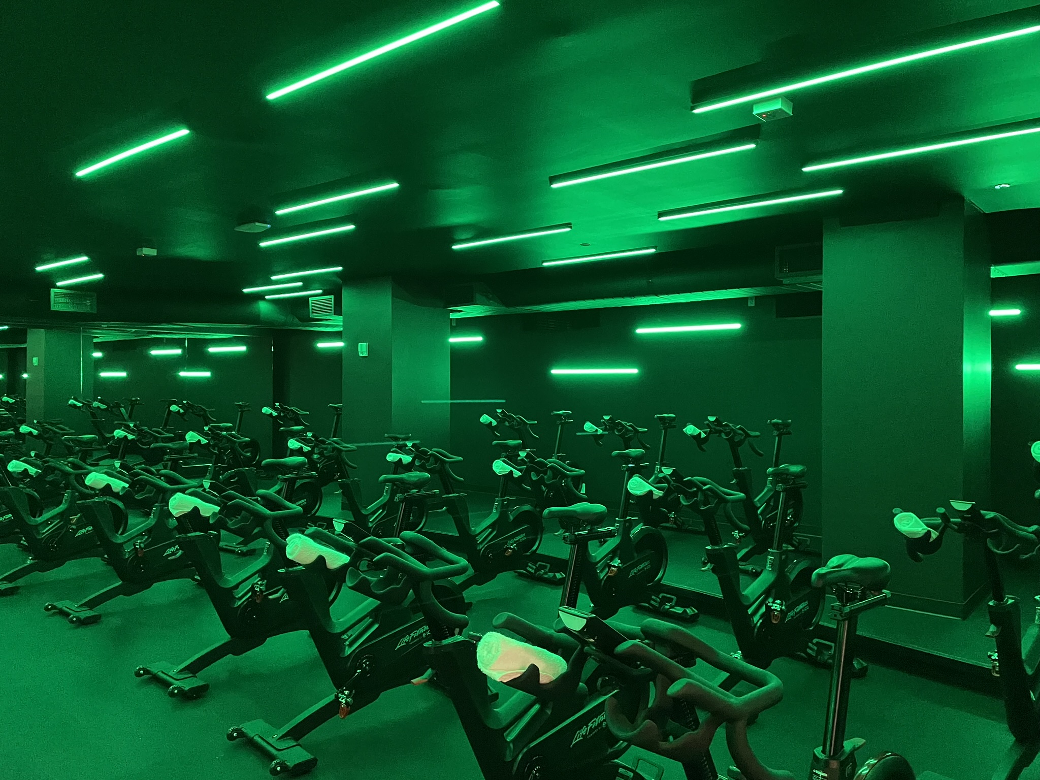 Chelsea Piers Fitness cycling studio with green linear lighting